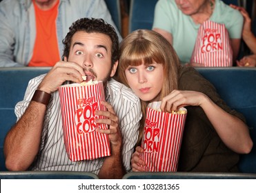 Captivated couple  with popcorn bags in a theater - Powered by Shutterstock