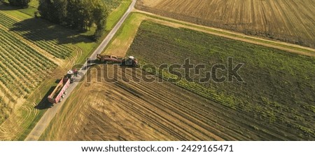 A captivating aerial perspective showcases a powerful tractor gracefully pulling a massive tractor trailer through a vast field, their synchronized movements