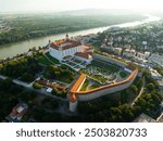 Captivating aerial photograph showcasing Bratislava Castle with garden, the winding Danube River, and the surrounding cityscape in Slovakia.