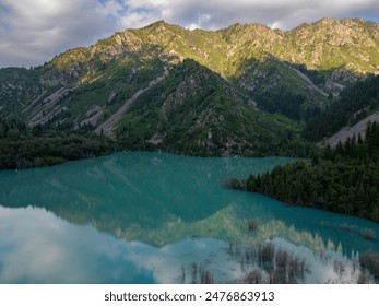 Captivating aerial view of a serene mountain lake, encircled by lush greenery and rugged hills, reflecting the vibrant sky at sunset - Powered by Shutterstock