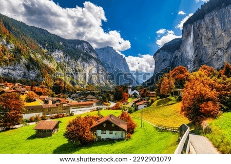 Captivating autumn view of Lauterbrunnen valley with gorgeous Staubbach waterfall and Swiss Alps at sunset time. Lauterbrunnen village with autumn red foliage, Berner Oberland, Switzerland, Europe.