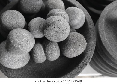A captivating close-up of a pile of traditional Indonesian mortar and pestle made from volcanic rock. It is a traditional Indonesian tool for grinding herbs and spices