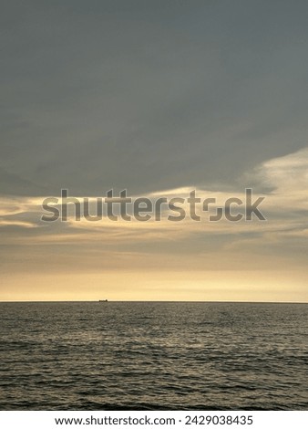 A captivating coastal sunrise scene with a lone figure standing by the shore, basking in the warm glow of the morning sun, creating a serene and contemplative atmosphere.