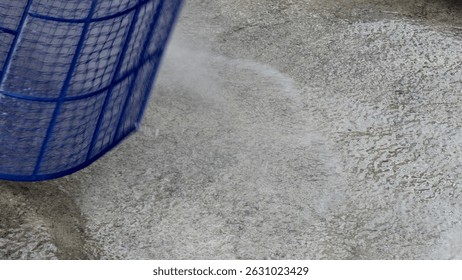 A captivating image featuring water splashing from a blue basket onto a grey textured surface, symbolizing motion and vitality in everyday activities.