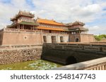 A captivating image of the iconic Imperial Citadel of Hue, Vietnam. The imposing main gate, with its intricate carvings and vibrant yellow roof, stands as a testament to the grandeur of the Nguyen Dyn