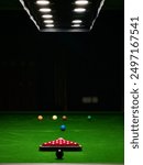 A captivating image of a snooker table illuminated by overhead lights, showcasing a perfectly arranged set of snooker balls. Ideal for sports enthusiasts and game room decoration