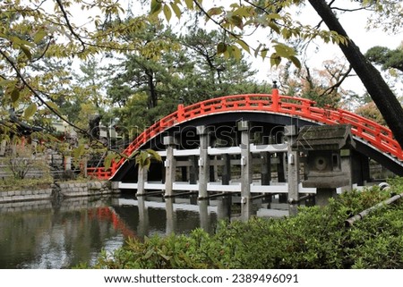 Captivating images of popular locations in Osaka, Japan, showcasing Sumiyoshi Taisha, an ancient shrine, with a striking red arch bridge elegantly mirrored on the tranquil water surface.