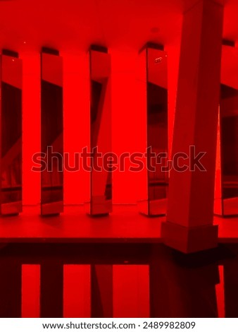 A captivating interior of the Louis Vuitton Foundation in Paris, featuring intense red lighting and reflective columns. The modern design and dramatic atmosphere create a visually striking experience.