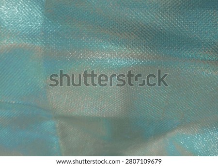 Captivating Iridescent Textile Texture

This image highlights a stunning close-up of an iridescent fabric, revealing its unique texture and mesmerizing color play. The soft sheen glimmers in hues of blue and green, creating a dynamic visual as light interacts with the surface. Fine patterns weave throughout the material, adding depth and interest. Ideal for fashion, accessories, or artistic projects, this fabric stands out for its elegant and luxurious quality. Its captivating nature makes it perfect for designs that aim to evoke creativity and charm, enhancing any decorative or wearable item beautifully.