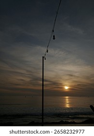 A captivating ocean sunset with a string of lights silhouetted against the sky, creating a serene and moody atmosphere. Perfect for travel, events, or peaceful escape themes. #CoastalSunset