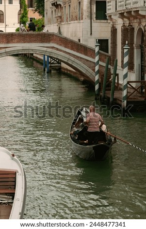 A captivating photo capturing a gondolier skillfully navigating the iconic canals of Venice, Italy, with historic buildings and picturesque bridges forming a charming backdrop against the serene water