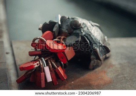 A captivating photo capturing a metal frog sculpture biting a multitude of padlocks symbolizing the unbreakable bonds of love and union among couples. 