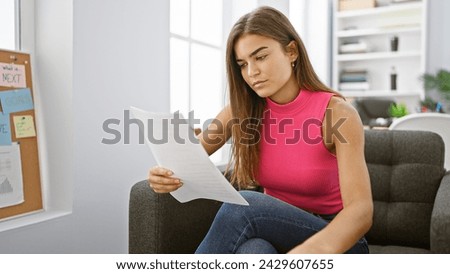 Captivating portrait of a young, beautiful hispanic woman engrossed in reading a business document, a focused employee hard at work in the office