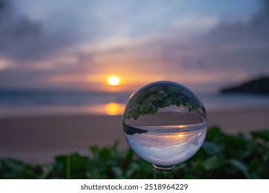 A captivating sunset reflected through a crystal ball, creating an inverted and artistic perspective of a serene beach scene at dusk. sweet sky in sunset over the sea background.