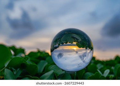 A captivating sunset reflected through a crystal ball, creating an inverted and artistic perspective of a serene beach scene at dusk. sweet sky in sunset over the sea background.