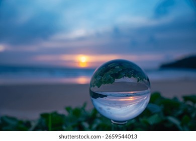 A captivating sunset reflected through a crystal ball, creating an inverted and artistic perspective of a serene beach scene at dusk. sweet sky in sunset over the sea background.