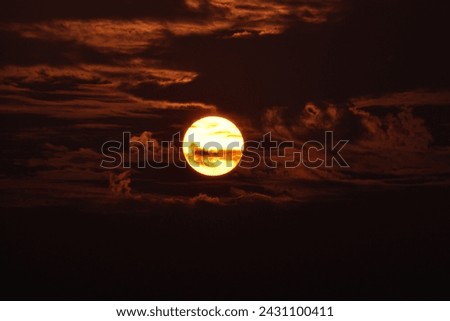 A captivating sunset scene with the sun partially obscured by clouds. The interplay of light and shadow creates a dramatic and atmospheric setting, perfect for evoking a sense of beauty in nature.
