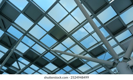 Captivating view of a modern architectural glass ceiling structure against a clear blue sky, showcasing geometric design and urban innovation. - Powered by Shutterstock