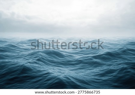 A captivating view of ocean waves rolling gently under a soft, cloudy sky, creating a peaceful and calming seascape. The water reflects the sky's muted tones.