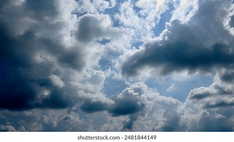 A captivating view of a partly cloudy sky with a mix of dark and light clouds, revealing patches of blue sky. The image showcases the dynamic nature of weather conditions during summer.