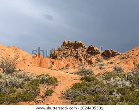 A captivating view of red rock formations under a dramatic sky, showcasing the raw beauty of an arid landscape.