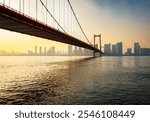 A captivating view of a suspension bridge spanning the Yangtze River at sunset, surrounded by Wuhan