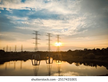 captivating view of towering power lines reflected over the calm waters of a lake during sunset. - Powered by Shutterstock