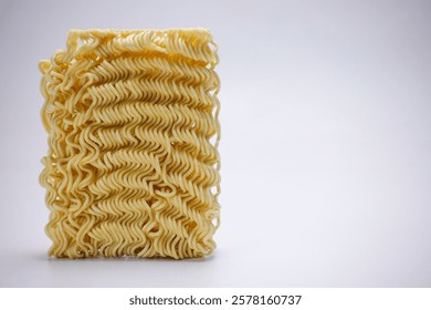 A captivating view of uncooked instant noodles, their goldenyellow curls stacked neatly, creating a simple yet striking image. The texture and detail are captivating.