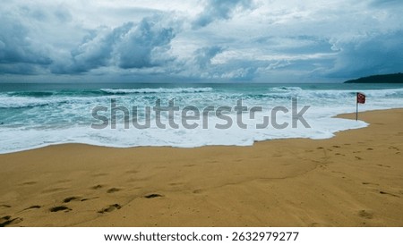 A captivating view of waves hitting the shore showcasing nature's beauty and a warning flag signaling caution.