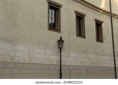 A captivating wall of a historic building prominently features intricate windows alongside an adjacent decorative street lamp, beautifully framed within a vibrant urban setting - Powered by Shutterstock