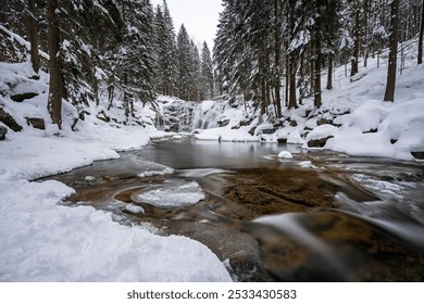 Captivating Winter Landscape: Frozen Waterfall Cascading into a Flowing River Surrounded by Snow-Covered Coniferous Trees - A Breathtaking Display of Nature's Icy Beauty - Powered by Shutterstock