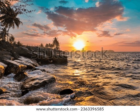 Capture Beautiful Sea Scape and half Landscape in Beautiful Sunset. The photo with thousands stories. Sunset photo. sea water and reflection. Rocks, Grass, and coconut trees beside the beach.
