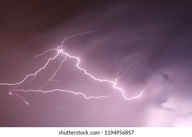 Capture of a split second moment where lightning flashed during a storm which produced a purple hue in the sky.