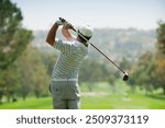 Capture the thrill of golf with this high-resolution image showcasing a golfer in mid-swing on a lush green fairway. The golfer, dressed in modern athletic wear, demonstrates perfect form as they stri