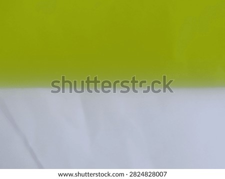 Captured in a clean full-frame studio shot, this minimal dual-tone photograph features a sharp horizontal split composition dividing a vibrant chartreuse green field above and a soft off-white surface below.