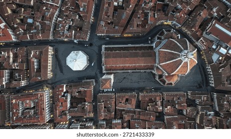 Captured from a drone's perspective, this stunning aerial photograph showcases the intricate rooftops of historical buildings, with a focus on the beautifully designed domed church in the heart of the city. The soft morning light enhances the rich terracotta tones, creating a captivating view of urban architecture surrounded by tightly packed structures.