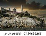 Captured at the historic Alcatraz Island, this image showcases the Alcatraz lighthouse standing stoic against a fiery sunset, with seagulls soaring in the golden sky.