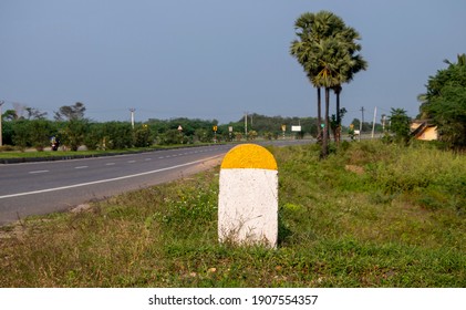 Captured Real Photo of Plain Yellow and White Milestone with National Highway Road and green plants Background which can be used for writing Kilometre numbers on it found in Tamilnadu South India Asia