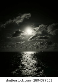 Captures a dramatic and moody nightscape over the open ocean. A bright full moon pierces through dark, scattered clouds, casting a stark, silvery glow across the night sky. This intense light creates a mesmerizing, shimmering reflection that stretches across the rippling surface of the dark sea, contrasting beautifully with the deep shadows of the water and the silhouette of the clouds. The overall atmosphere is serene yet mysterious, highlighting the raw, quiet majesty of nature at night.
#Nightscape #OceanAtNight #FullMoon #Moonlight #SeascapePhotography #MonochromeVibes #DarkAesthetics #CloudyNight #DramaticSky #NaturePhotography