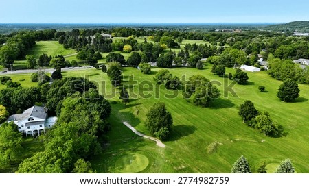 Capturing an area of the golf course as vehicles drive by on the adjacent street that delineates the extent of the course on one side.