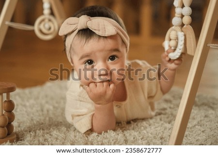 Capturing Candid Moments: The photo captures the innocence of early childhood as a one-year-old finds comfort in simple actions like chewing her fingers while amidst wooden toys
