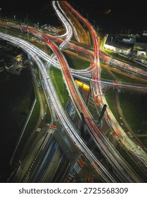 Capturing the dynamic flow of traffic on a complex urban highway system during nighttime hours, showcasing the mesmerizing streaks of vehicle lights