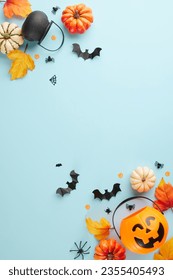Capturing the enigmatic magic of Halloween. Top view vertical photo of pumpkin basket, witch brooms, pots, pumpkins, autumn leaves, halloween decorations on light blue background with ad space - Shutterstock ID 2355405493