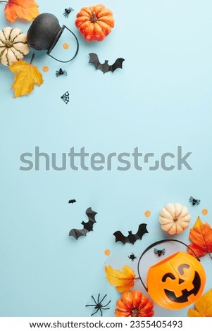 Capturing the enigmatic magic of Halloween. Top view vertical photo of pumpkin basket, witch brooms, pots, pumpkins, autumn leaves, halloween decorations on light blue background with ad space