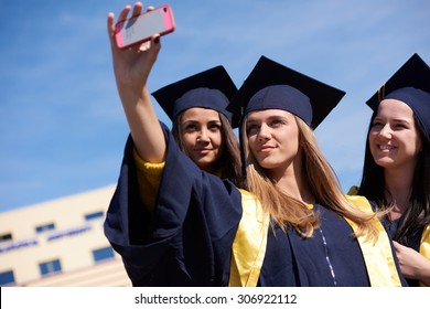 Capturing A Happy Moment.Students Group  College Graduates In Graduation Gowns  And Making Selfie Photo