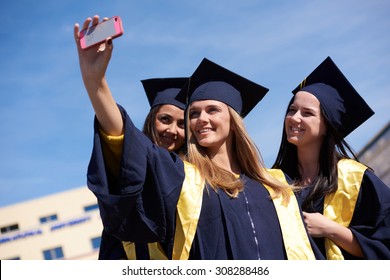 Capturing A Happy Moment.Students Group  College Graduates In Graduation Gowns  And Making Selfie Photo