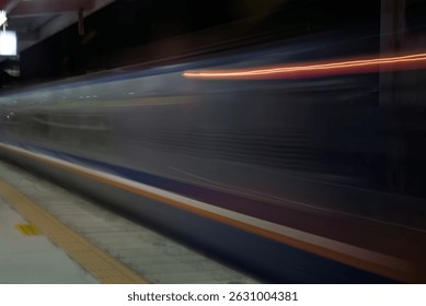 Capturing a long exposure shot of a train passing by at night, leaving colorful light trails. The silver train reflects nearby lamp light, creating additional highlights in the scene.