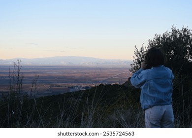 Capturing the Moment: A Woman Photographs the Sunset Over the Mountain Plateau - Powered by Shutterstock