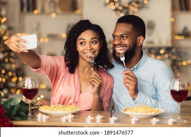 Capturing Moments. Beautiful Lovely Young African American Couple Taking Selfie While Sitting At Table And Having Dinner. Smiling Woman And Man Eating Pasta And Having Fun At Restaurant Or At Home