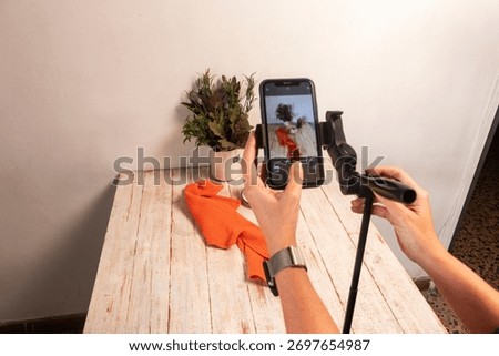 Capturing the perfect flat lay for a coffee brand's social media. A smartphone is used to photograph a setup with earth tones and a wooden texture. Focus on mobile photography trends.